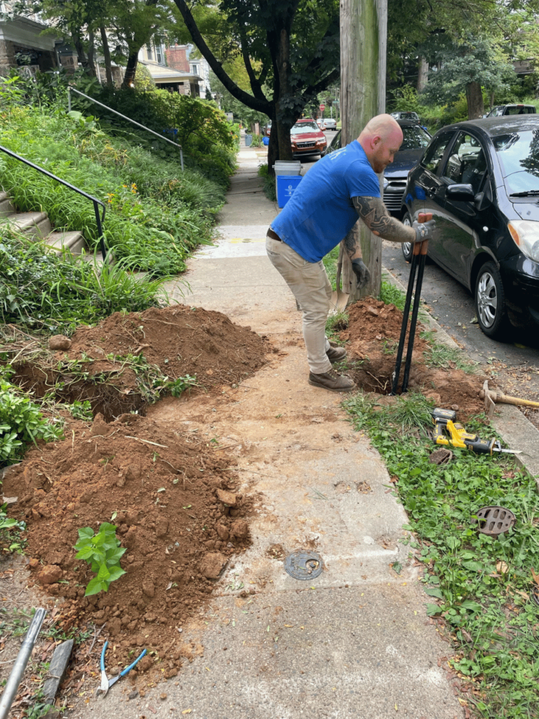 Ev car charger post getting dug with a post hole tool.