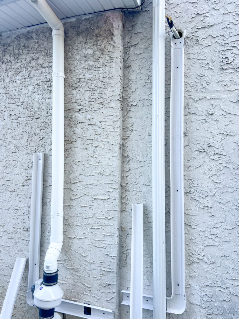 GEN3 Electric & HVAC technicians preparing exterior PVC linehide for a Mitsubishi ductless mini-split installation in Roxborough, Philadelphia, showing partially assembled conduit and insulated refrigerant lines for a clean, professional finish.