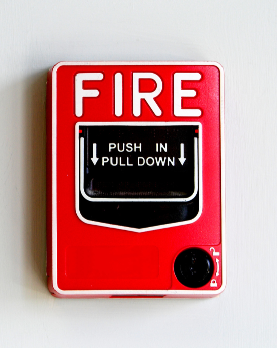 Red fire alarm pull station on a wall, symbolizing home fire safety and emergency preparedness